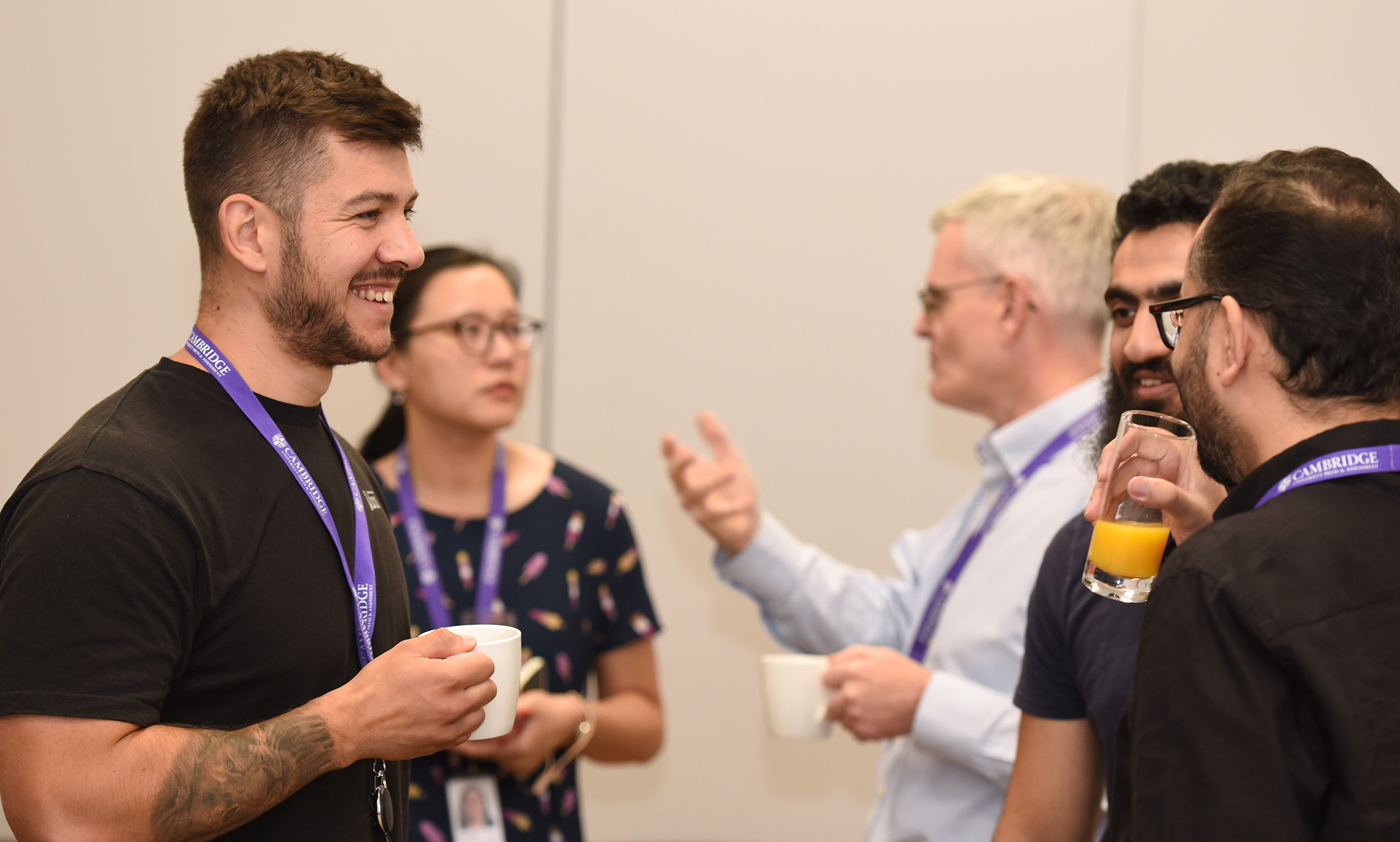 Two seperate groups of Cambridge colleagues having conversations and enjoying cups of beverages at the data apprentice celebration held in Cambridge.